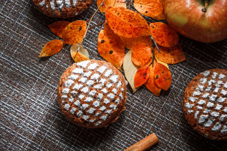 Chocolate muffins with apple filling on a background of autumn leaves and cinnamon