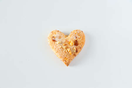 One heart shaped cookie on a white background. One sugar cookie with almond on a white background.の写真素材