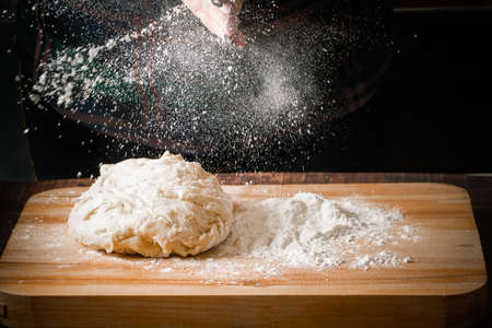 Flour pouring from hands onto pizza dough