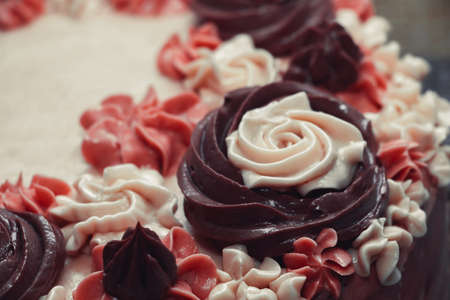 Pink birthday cake with cream flowers on a dark backgroundの写真素材