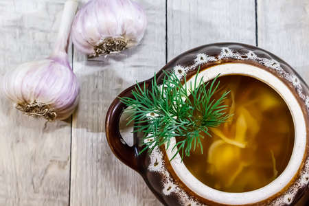 Vegetable soup in a pot with bread and fresh garlic on a gray wooden backgroundの写真素材