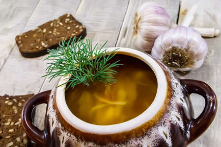Vegetable soup in a pot with bread and fresh garlic on a gray wooden backgroundの写真素材