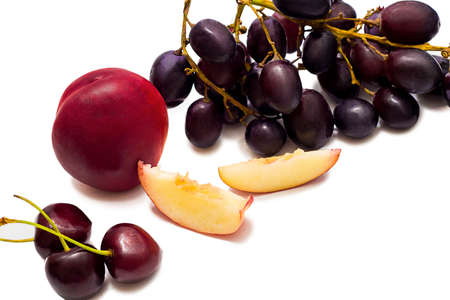 Juicy nectarine and slices and dark grapes isolated on white backgroundの写真素材