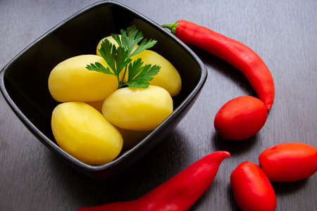 Boiled potatoes with chili peppers and tomatoes on a dark backgroundの写真素材