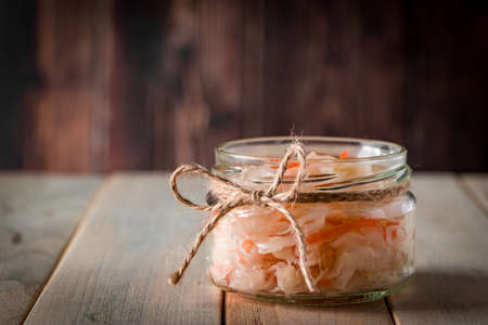 Homemade sauerkraut on a dark brown background. Fermented cabbage in a jar on a wooden background. Eco food, the trend of healthy eating. Place for your text.の写真素材