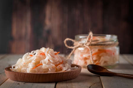 Homemade sauerkraut on a dark brown background. Fermented cabbage in a jar on a wooden background. Eco food, the trend of healthy eating. Place for your text.の写真素材