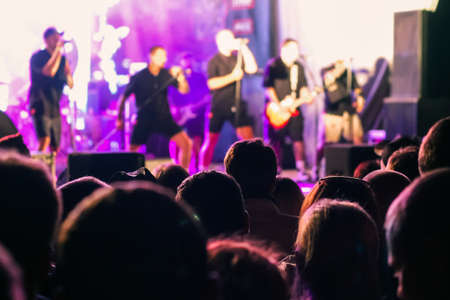 A crowd of people watching a musical group performing on stageの写真素材