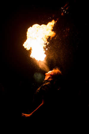 Man exhaling fire on a black background. Fire showの写真素材