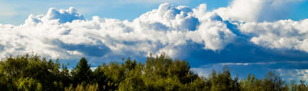 Landscape with beautiful fluffy clouds on a blue sky. Banner format for design.