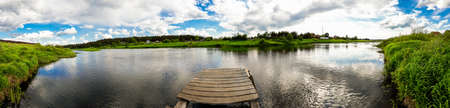 Old wooden pier on the river. Panoramic countryside view