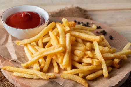 Hot golden french fries with sauce on a wooden background. Homemade rustic food.