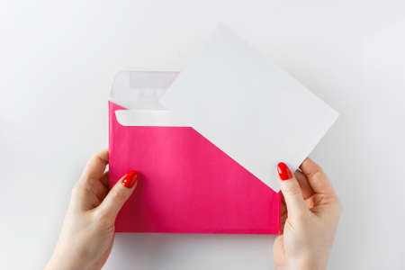 Envelope with a letter in hands on a white background. Pink envelope in hands on a white background....