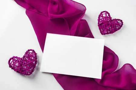 Red hearts and silk ribbon on a white background. Valentine's day empty greeting card on the background of two hearts and a red silk ribbonの写真素材