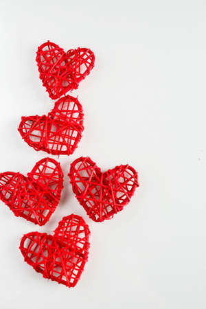 Red handmade hearts made of twigs on a white background. A lot of red hearts from twigs of vines on...