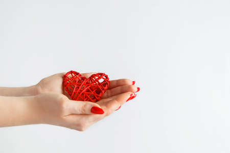 Hands holding a red heart on a white background. The concept of health and love. Hands of a young...