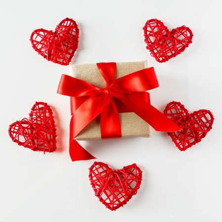 Valentine's day gift and red hearts on a white background. Gift in craft paper with a red ribbon...