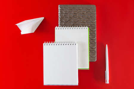 Minimalistic layout for design. Office supplies - notebooks and pens on a red background.の写真素材