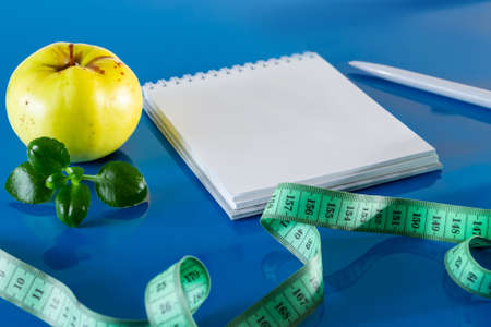 The concept of diet and proper nutrition. Fruits and measuring tape on a blue background. Layout for design, healthy food and lifestyle. Quarantine Endの写真素材
