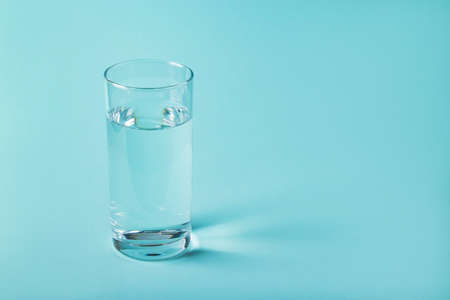 Glass of clear water on a blue background. Health concept, place for text.