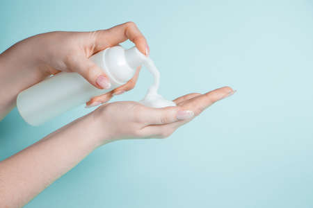 A young woman uses antibacterial soap to disinfect her hands. Coronavirus prevention, health protection concept.の写真素材