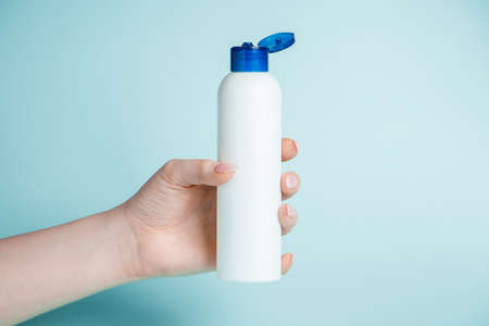 Disinfectant bottle in hand close-up on a blue background. Coronavirus prevention, health protection concept.の写真素材