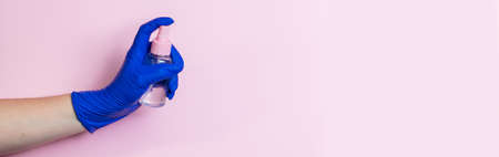 A hand in a blue latex glove holds a disinfectant. The concept of preventive protection against coronavirus. Use of antiseptics for cleaning.の写真素材