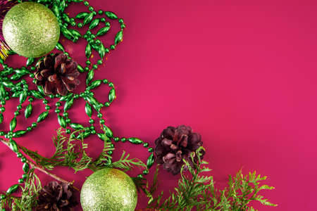 Christmas decor - cones, Christmas balls and branches on a pink background. Aroma candle for a pleasant holiday. Place for your text.の写真素材