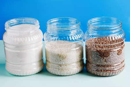 Jars with cereals and sugar on a blue background. Shopping essentials in home quarantine.の写真素材