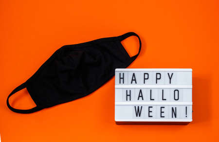 Protective mask on an orange background. Happy Halloween 2020. Concept of protection against coronavirusの写真素材