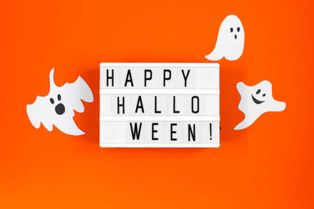 Halloween concept. Festive decorations - paper ghosts and spider web on an orange background.の写真素材