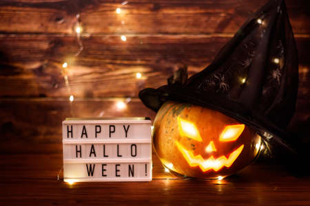 Happy Halloween! Pumpkin in a witch hat on a wooden background. Place for text.の写真素材