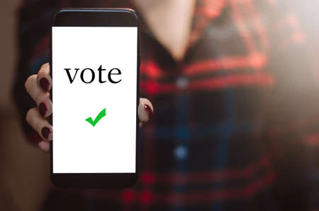 Woman votes online using the phone. Voting and elections concept. Place for text