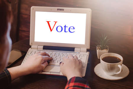 Woman votes online using laptop. Voting and elections concept. Work space at home.の写真素材