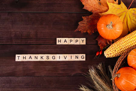 Happy Thanksgiving Day. Ripe orange pumpkins, wheat and corn on a brown wooden background.