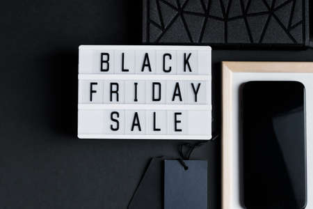 Black Friday sale. Smartphone and accessories on a dark background. Monochromatic flatlay, online shopping concept.の写真素材