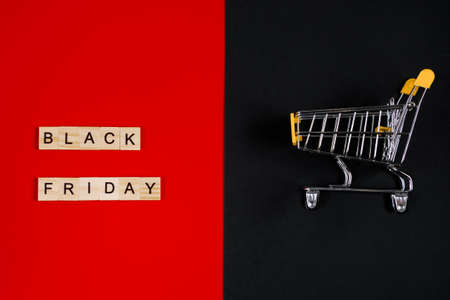 Black Friday sale concept. Mini shopping cart and sign on a red background. Banner for advertising.
