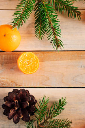 Christmas decor. Fir branches, cones and tangerines on a wooden background.の写真素材