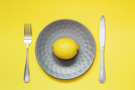Gray plate with lemon on a yellow background. Trending colors 2021 - Ultimate gray and illuminating.の写真素材