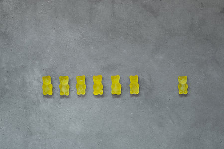 Yellow gummy bears on concrete background. Color of the year 2021 is ultimate gray and illuminating.の写真素材