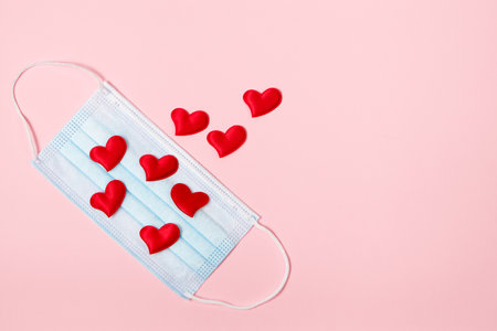 Valentine's day concept during the coronavirus pandemic. Pink heart and medical mask. Place for text.の写真素材