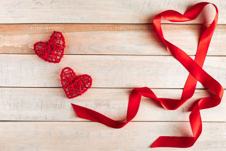 Red silk ribbon in shape of heart on wooden background. Valentine's day concept. Place for text.の写真素材