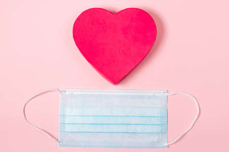 Valentine's day concept during the  virus pandemic. Pink heart and medical mask. Place for text.の写真素材
