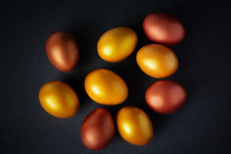 Luxurious golden Easter eggs. Festive decor on black background. Place for text.