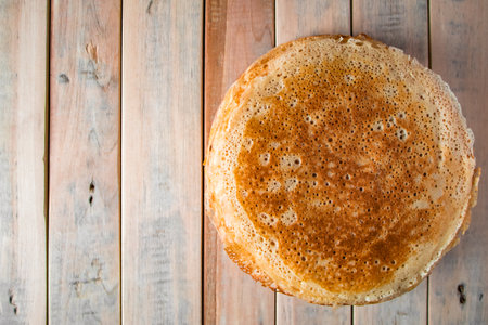 Appetizing thin pancakes on a wooden background. Russian food for the holiday Maslenitsa. Top view,...
