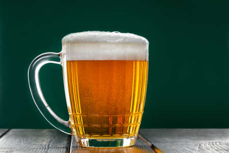 Mug with traditional Irish pale ale on dark green background. Bubbles in glass of beer.の写真素材