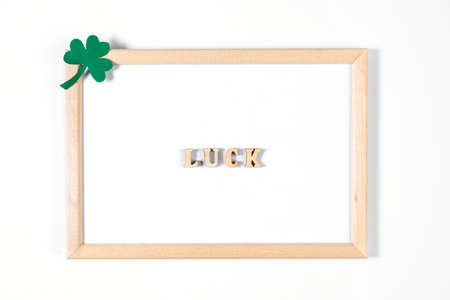Minimalistic flatlay for St. Patrick's Day. Shamrock and frame on white background. Happy Irish holiday, symbols of good luck.の写真素材