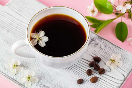 Cup of strong espresso coffee and delicate spring flowers on pink background. Springtime and good...