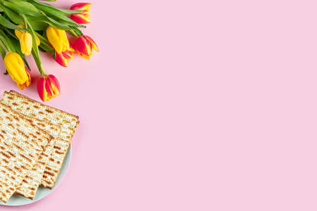 Happy Passover banner. Matzo and a bouquet of colorful tulips on pink background. Traditional Jewish food for Pesach.の写真素材