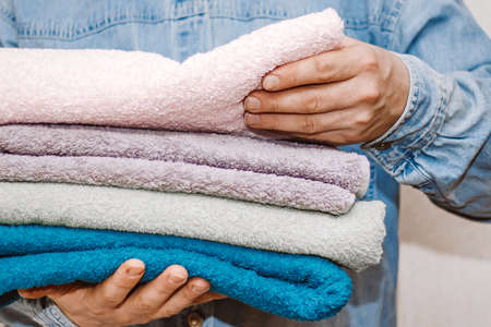 Man holds stack of fresh terry towels. Organization and cleaning of house. Storage and housekeeping conceptの写真素材