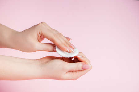 Hand care concept. Young woman remove nail polish on a pink background. Place for text.の写真素材